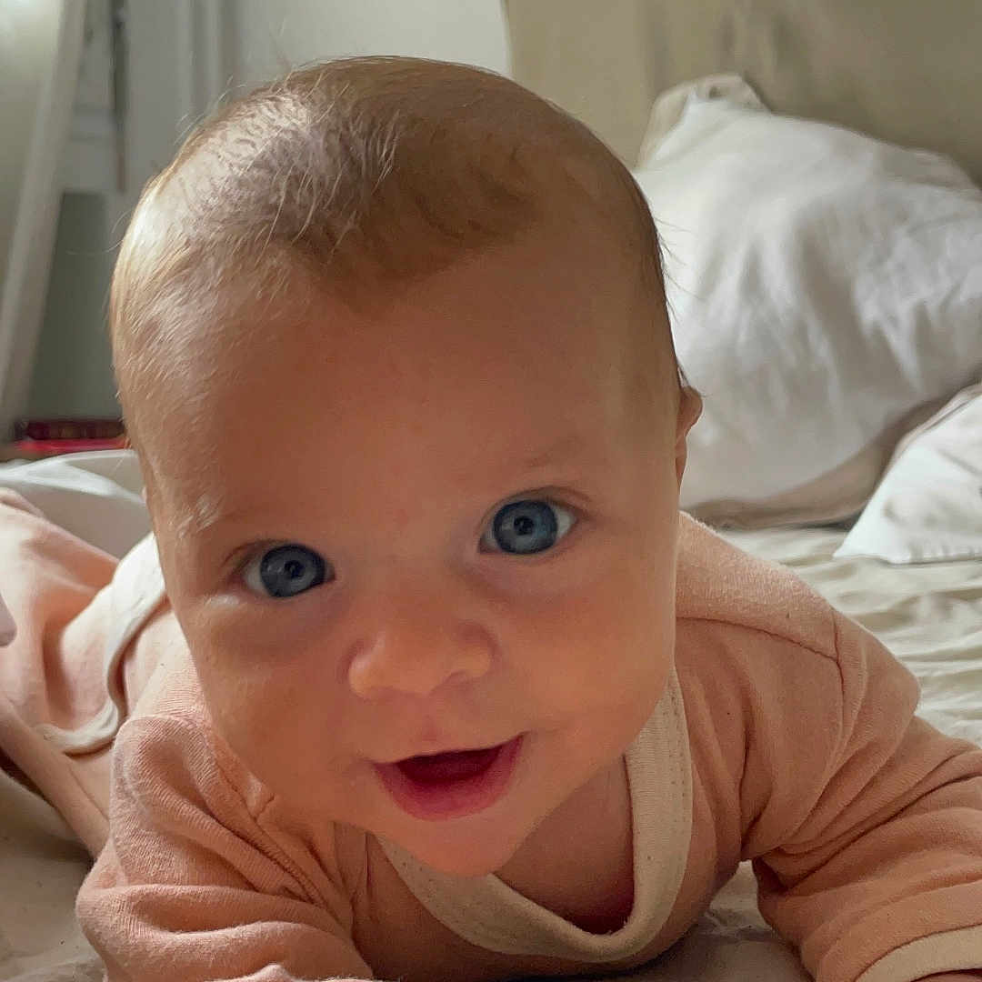 Ambre participe au concours pour gagner de l'argent avec cette photo : baby, bed, blue_eyes, child, closeup, cozy, cute, hand, happy, head, indoors, infant, lying_down, person, pillow, portrait, skin, sleepwear, smiling, soft_light