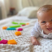 Ambre participe au concours pour gagner de l'argent avec cette photo : baby, smiling, blanket, toy_blocks, indoor, child, happy, face, infant, colorful, play, texture, closeup, cute, young, person, soft, hands, comfort, lying_down
