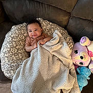 Nova joined the competition — help win amazing prizes! baby, blanket, couch, plush_toy, pillow, smile, infant, cozy, patterned, furniture, child, soft, cute, indoors, relaxing, happy, person, toy, comfort, small