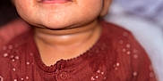 Nova is registered to the contest to win money with this photo: baby, child, face, smile, closeup, maroon_clothing, patterned_clothing, infant, cute, portrait, soft_background, eyes, skin, head, person, young, happy, indoors, warm_tone, expression