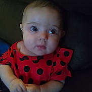 Yazmin is registered to the contest to win money with this photo: baby, child, infant, polka_dot, red_dress, curious, hands, portrait, indoor, cute, person, face, young, sitting, clothing, expression, skin, head, small_hands, dark_background
