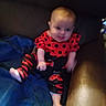 Yazmin is registered to the contest to win money with this photo: baby, infant, child, red_clothing, black_clothing, ladybug_outfit, blanket, couch, furniture, indoor, person, sitting, cute, young_child, soft_lighting, blur, cozy, home, portrait, infant_clothing