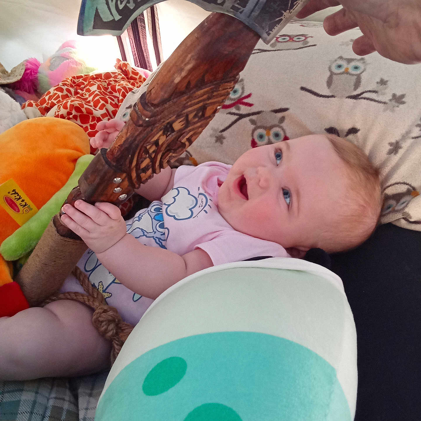 Yazmin joined the competition — help win amazing prizes! baby, infant, toy, axe, plush_toy, blanket, owl_pattern, hand, smiling, blue_eyes, clothing, pink_shirt, indoor, child, cute, playful, cushion, rope, person, happy