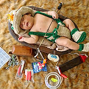 Thomas is registered to the contest to win money with this photo: baby, sleeping, crochet_outfit, fishing_rod, fishing_tackle, wooden_bowl, fur_rug, toy, baby_hat, baby_booties, brown_leather_bag, fishing_bobbers, fishing_hooks, fishing_lures, baby_clothing, child, indoors, resting, cute, props