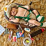 baby, sleeping, crochet_outfit, fishing_rod, fishing_tackle, wooden_bowl, fur_rug, toy, baby_hat, baby_booties, brown_leather_bag, fishing_bobbers, fishing_hooks, fishing_lures, baby_clothing, child, indoors, resting, cute, props