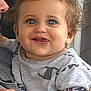 toddler, child, curly_hair, blue_eyes, smiling, tongue_out, grey_shirt, champion_logo, person, baby, cute, holding, indoor, happy, face, portrait, skin, hand, arm, closeup