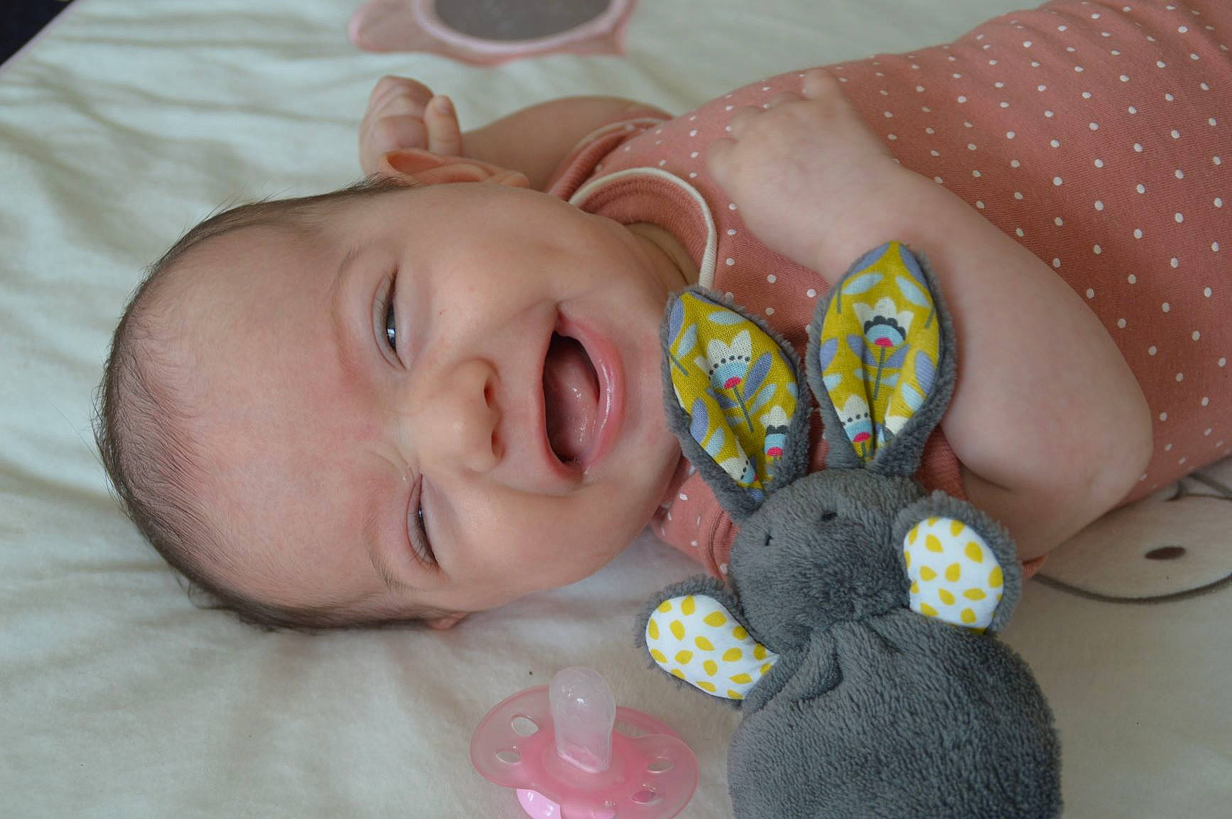 Amélie participe au concours pour gagner de l'argent avec cette photo : arm, baby, baby_toddler_clothing, cheek, ear, facial_expression, finger, hand, happy, human_body, nose, organ, person, pink, product, skin, smile, textile, toy, white