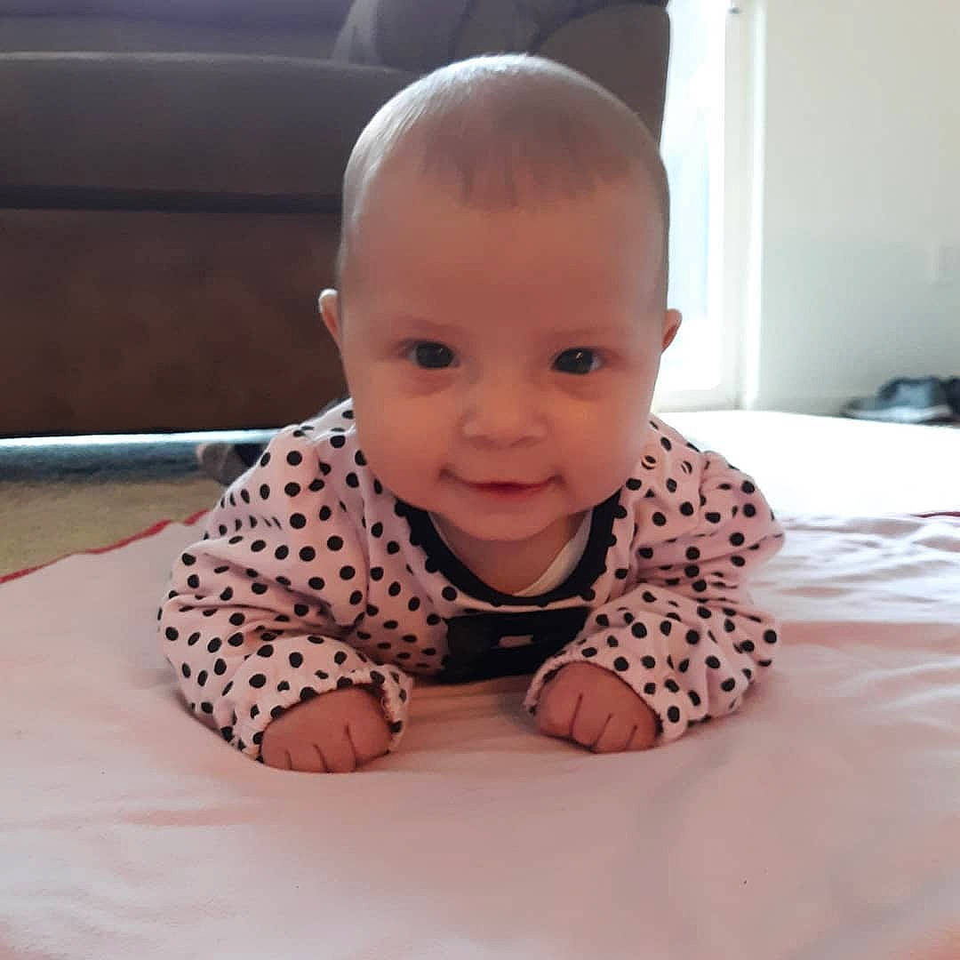 Kiara is registered to the contest to win money with this photo: baby, baby_products, baby_toddler_clothing, cheek, child, crawling, design, ear, eye, face, forehead, head, pattern, person, polka_dot, sitting, skin, smile, toddler, tummy_time