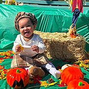 Yamanie joined the competition — help win amazing prizes! autumn, child, costume, decoration, fall, festive, happy, hay_bale, headwear, leaves, outdoor, plaid_skirt, playful, pumpkin, seasonal, sitting, smiling, sunflower, toddler, toy