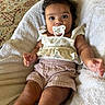 Delilah is registered to the contest to win money with this photo: baby, pacifier, towel, carpet, clothing, infant, person, cute, curly_hair, indoors, soft_texture, casual, relaxed, child, portrait, skin, hand, legs, sitting, looking