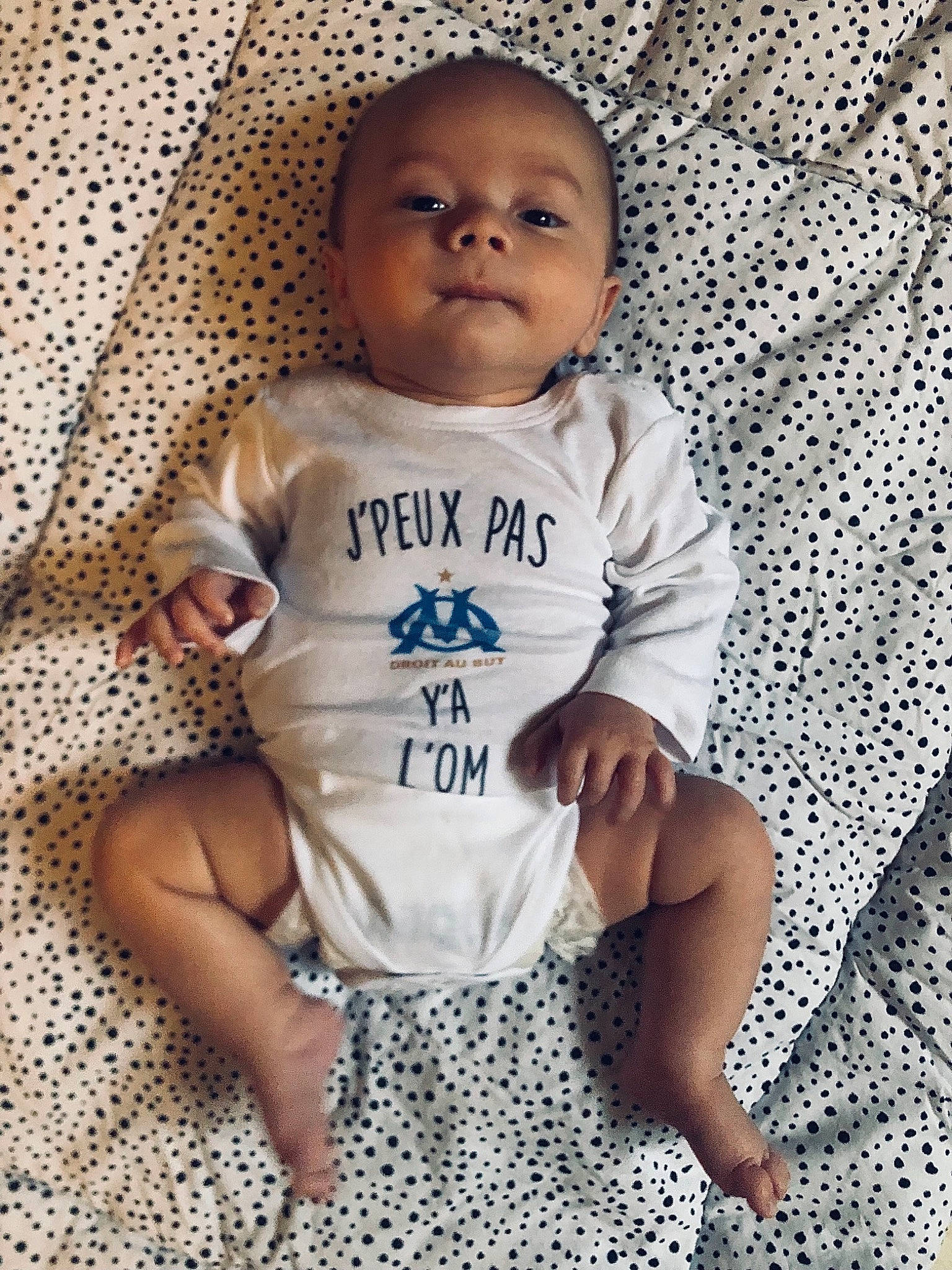 Gabin participe au concours pour gagner de l'argent avec cette photo : baby, baby_products, baby_toddler_clothing, cheek, child, comfort, face, finger, flooring, happy, linens, nose, outerwear, pattern, person, skin, sleeve, smile, t_shirt, textile