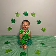 Makenai joined the competition — help win amazing prizes! toddler, child, smiling, green_bowtie, green_pants, bare_chest, shamrocks, st_patricks_day, green_cup, floor_covering, decorations, celebration, happy, indoor, curly_hair, cute, sitting, tooth_grin, festive, party