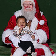 Makenai is registered to the contest to win money with this photo: baby, beard, black_pants, celebration, child, christmas, festive, glasses, gloves, happy, holiday, indoor, people, portrait, red_suit, santa_claus, smile, socks, sweater, white_fur