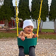 Makenai joined the competition — help win amazing prizes! beanie, casual_clothing, child, daylight, feet, fun, grass, happy, legs, outdoor, park, playground, seat, smiling, sweater, swing, toddler, trees, wood_chips, yellow_chains