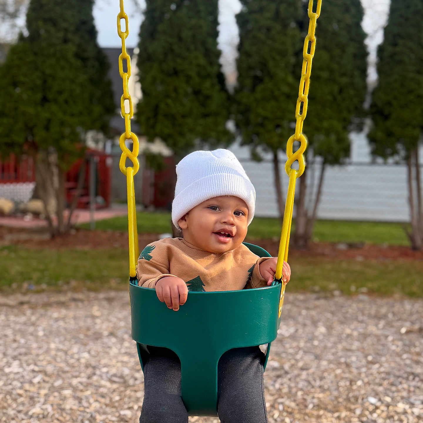 Makenai joined the competition — help win amazing prizes! beanie, casual_clothing, child, daylight, feet, fun, grass, happy, legs, outdoor, park, playground, seat, smiling, sweater, swing, toddler, trees, wood_chips, yellow_chains