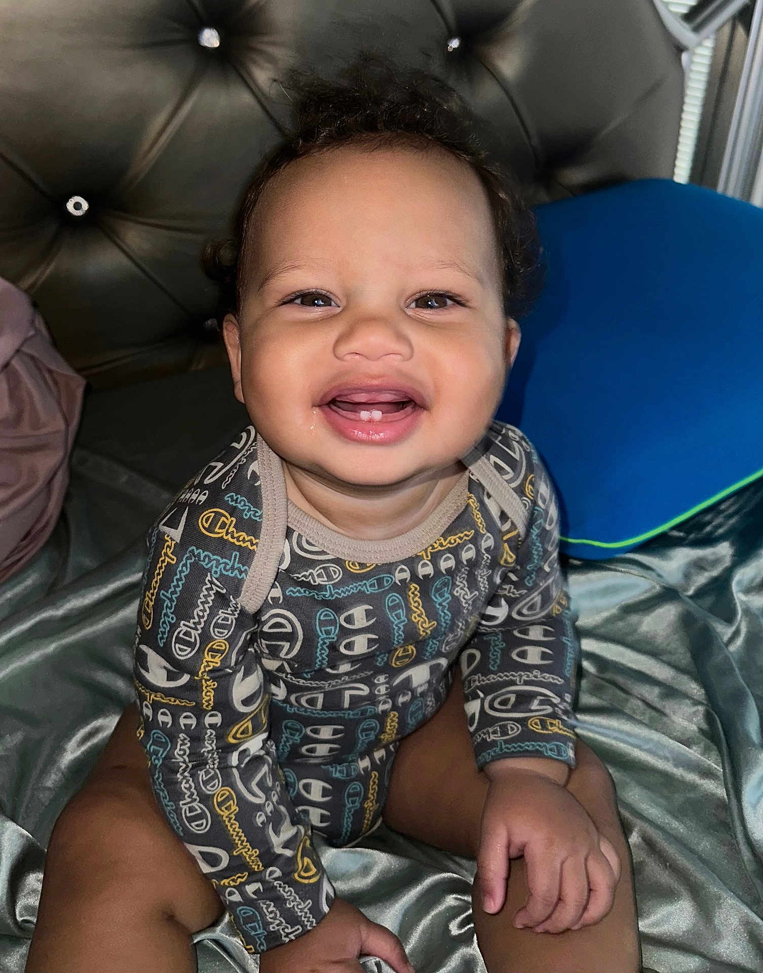 Makenai is registered to the contest to win money with this photo: baby, baby_girl, bed, blanket, child, clothing, curly_hair, cute, face, hands, happy, indoor, infant, onesie, person, pillow, portrait, sitting, skin, smile