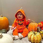 Makenai is registered to the contest to win money with this photo: autumn, baby, carpet, celebration, child, costume, cute, decor, fall, festive, happy, holiday, hoodie, indoor, lantern, orange_clothing, person, pumpkin, sitting, smile