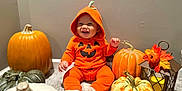 Makenai is registered to the contest to win money with this photo: autumn, baby, carpet, celebration, child, costume, cute, decor, fall, festive, happy, holiday, hoodie, indoor, lantern, orange_clothing, person, pumpkin, sitting, smile
