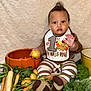 Makenai is registered to the contest to win money with this photo: baby, bib, carrot, child, cute, festive, food, greenery, harvest, holiday, indoor, kale, orange_bowl, portrait, potato, sitting, striped_pajamas, thanksgiving, vegetables, yellow_pot