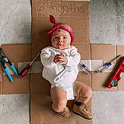 Kohen joined the competition — help win amazing prizes! baby, infant, diaper, bandana, face_paint, tools, cardboard, boots, floor, concrete, red_bandana, white_shirt, screwdriver, pliers, level_tool, curious_expression, child, indoors, hand_clasped, young_baby