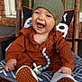 baby, child, smiling, laughing, hat, pacifier, beads, cushion, rocking_chair, wood, outdoor, brick_wall, pillow, clothing, footwear, cute, happy, infant, portrait, seat