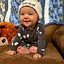 Kohen joined the competition — help win amazing prizes! baby, child, smiling, hat, couch, blanket, plush_toy, deer, knitted, brown, blue, white, clothing, foot, hand, face, indoor, cute, happy, person
