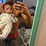 baby, casual, child, clothing, curious, family, holding, home, indoor, living_room, man, mirror, pajamas, person, phone, portrait, reflection, selfie, shirtless, technology