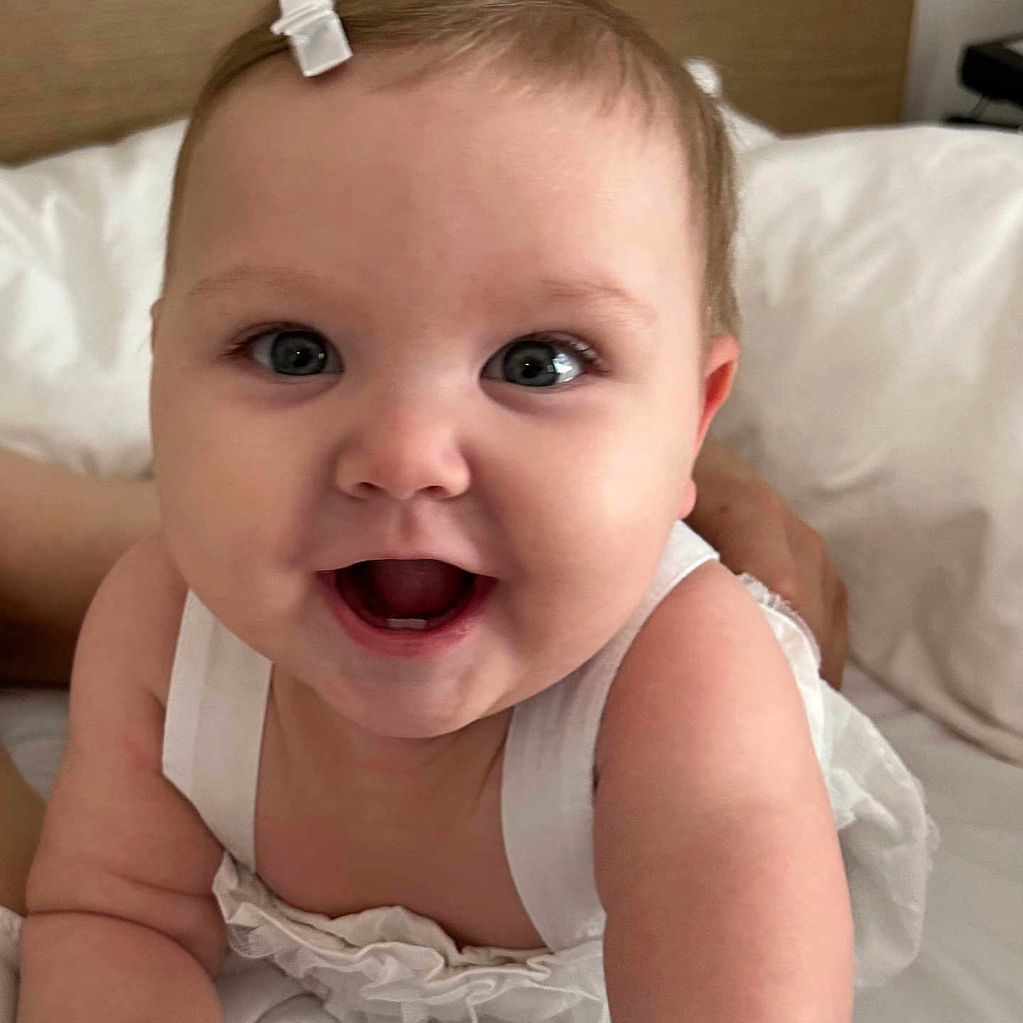 Juliet Marie Willey is registered to the contest to win money with this photo: baby, baby_girl, bed, child, closeup, cute, eyes, face, hair_clip, hands, happy, indoor, infant, pale_skin, person, portrait, smiling, soft_light, white_clothing, young_child