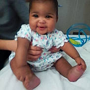 Zariah is registered to the contest to win money with this photo: baby, blur, child, colorful, cute, face, hair_tie, hands, happy, holding, indoor, infant, person, play, sitting, skin, smile, toy, white_surface, young