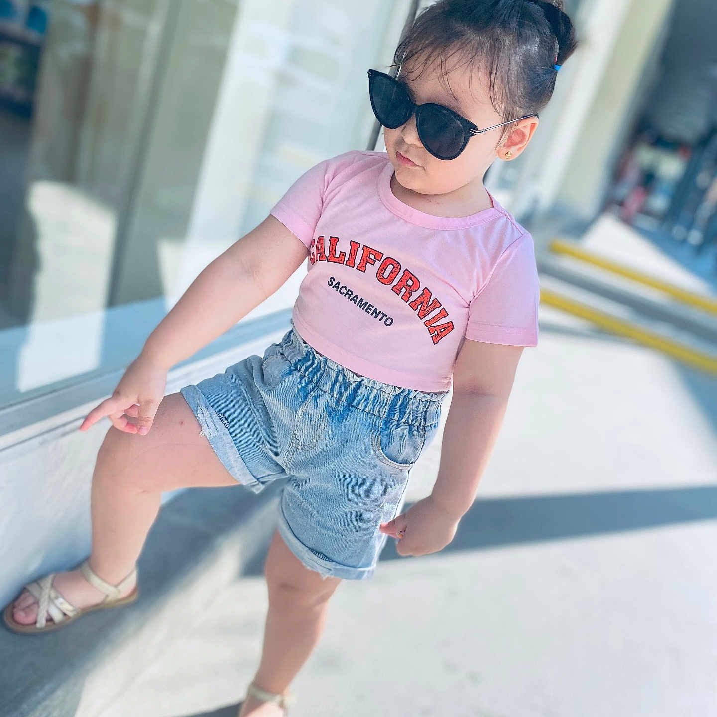 Rayssa participe au concours pour gagner de l'argent avec cette photo : accessories, baby, beachwear, blackhair, clothing, face, hair, head, jeans, pants, pedestrian, person, shorts, sitting, sleeve, sunglasses, t_shirt