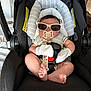 baby, car_seat, sunglasses, pacifier, mittens, infant, child, seatbelt, striped_clothing, black_car_seat, indoor, cute, small_feet, relaxing, casual, comfort, safety_harness, head_support, adorable, portrait