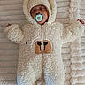 baby, sleeping, pacifier, onesie, fluffy, bear_costume, hood, blanket, soft_texture, infant, cute, cozy, child, laying_down, closed_eyes, warm_clothing, indoors, comfortable, adorable, resting
