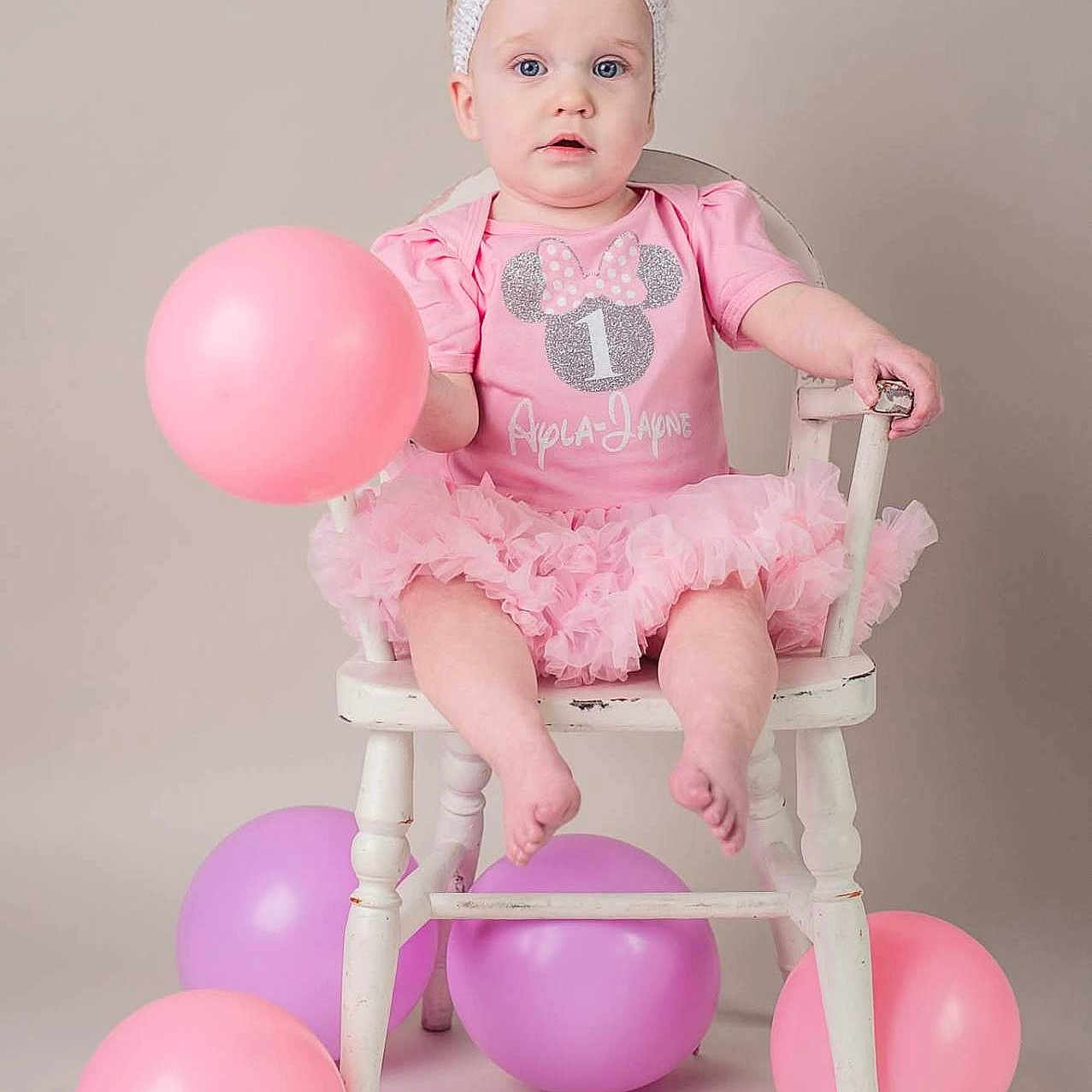 Ayla-Jayne is registered to the contest to win money with this photo: baby, balloon, celebration, chair, child, clothing, cute, expression, floor, headband, indoor, one_year_old, party, pastel_colors, person, pink, portrait, sitting, tutu, white_chair