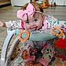 baby, child, infant, smiling, tongue_out, pink_bow, headband, blue_eyes, sitting, activity_walker, baby_toys, toy_rings, colorful, floral_clothing, patterned_mat, indoor, living_room, portrait, playtime, happy