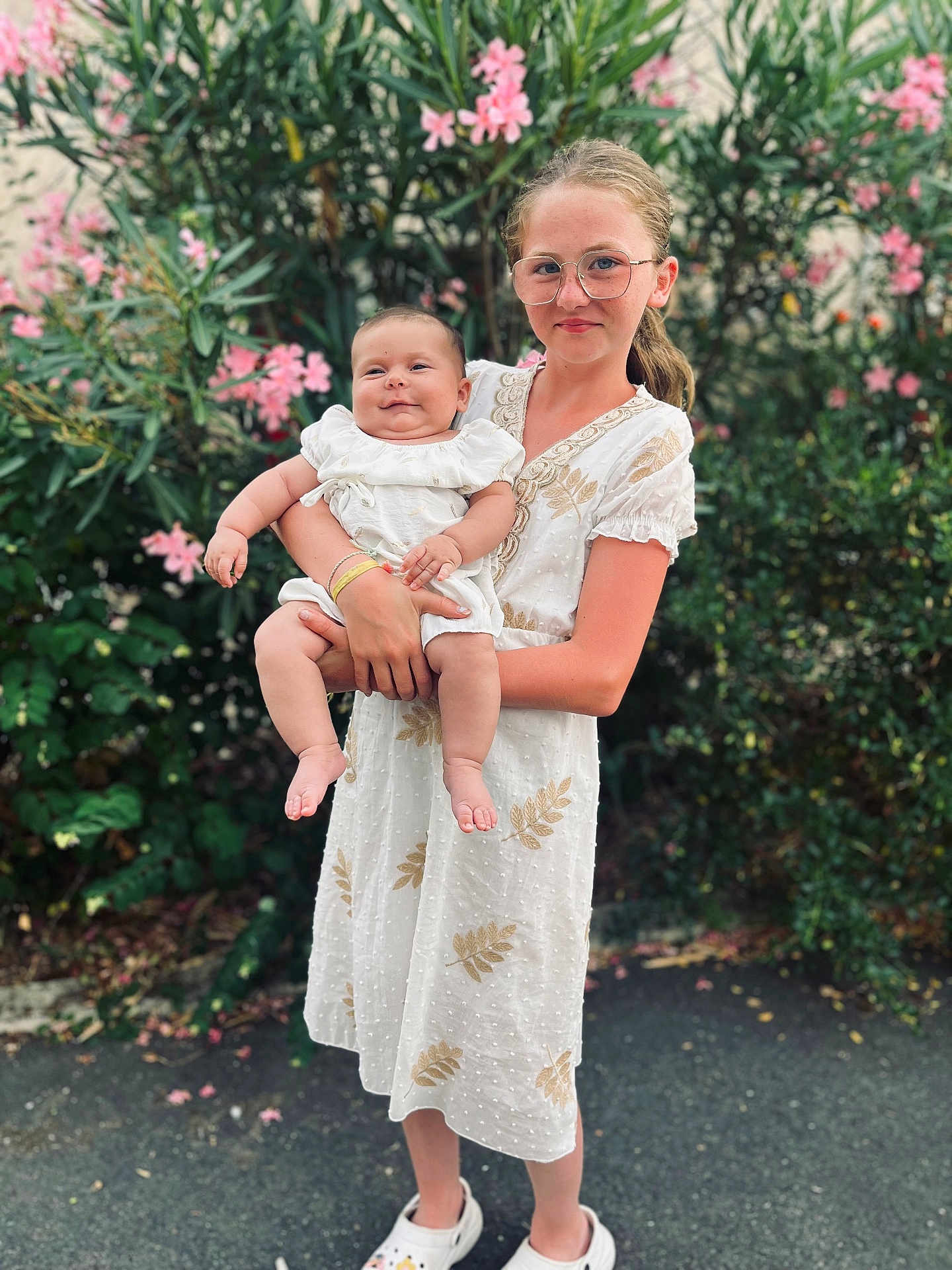 Lùcia a rejoint le concours — aidez-le/la à gagner de superbes lots ! child, baby, girl, glasses, white_dress, smile, outdoor, flower, greenery, nature, holding, happy, person, sibling, portrait, summer, plants, footwear, cute, family