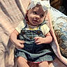 Myla joined the competition — help win amazing prizes! baby, child, headband, white_bow, denim_dress, blanket, pink_blanket, curious, soft_texture, indoors, couch, cushion, playful, infant, cute, smiling, person, portrait, young_child, seated