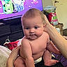 Theodore joined the competition — help win amazing prizes! baby, infant, child, portrait, sitting, supported, face, serious_expression, indoors, home, television, cartoon, adult_arm, diaper, bare_shoulders, furniture, entertainment_center, clutter, colorful_background, photography