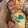 baby, infant, child, smiling, portrait, sitting, bouncer, baby_seat, striped_clothing, turtle, animal_pattern, blanket, cushion, indoor, home, sunlight, window, bamboo_shades, happy, face