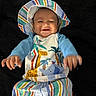 baby, child, smiling, hat, striped_clothing, colorful, infant, blue_sleeves, animal_print, happy, reaching_hands, portrait, cute, lying_down, playful, bright_colors, young_child, face, headwear, patterned_clothing