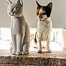 animal, calico_cat, calm, cat, ceramic_statue, companion, contrast, curious, cute, decor, feline, indoor, natural_light, pet, quiet, sculpture, side_view, still_life, stone_ledge, texture