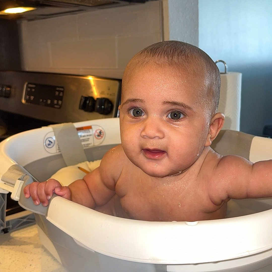 Cesar is registered to the contest to win money with this photo: baby, bathtub, bath_time, kitchen, countertop, child, infant, water_drops, face, skin, hand, curious_look, domestic, indoor, appliance, paper_towel, cleaning, cooking_area, cute, young_child