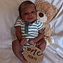 Taige is registered to the contest to win money with this photo: baby, child, cozy, cute, face, hands, indoor, infant, legs, newborn, one_month, onesie, portrait, sitting, smiling, soft_toy, striped_clothing, teddy_bear, white_blanket, wooden_sign