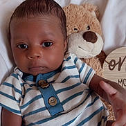 Taige is registered to the contest to win money with this photo: baby, child, cozy, cute, face, hand, indoors, infant, milestone, newborn, one_month, plush_toy, portrait, smiling, soft_lighting, striped_onesie, teddy_bear, white_blanket, wooden_sign, young