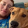 person, dog, face, portrait, indoor, couch, blue_shirt, red_hair, brown_dog, snuggle, close_up, relaxed, pet, companion, animal, friendship, casual, home, cozy, resting