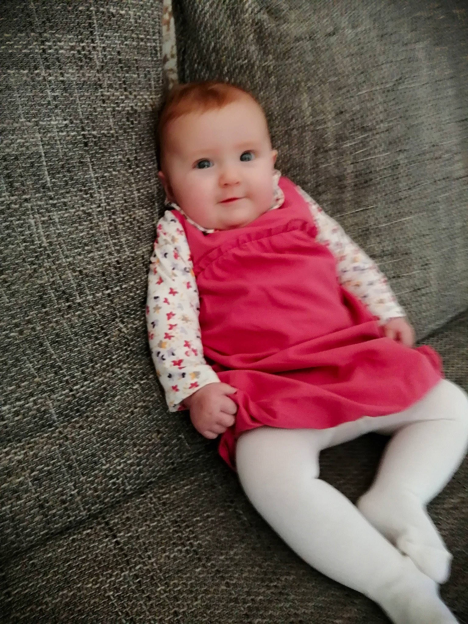 Lyzie participe au concours pour gagner de l'argent avec cette photo : baby, baby_toddler_clothing, cheek, child, dress, floor, flooring, foot, fur, hardwood, human_leg, knee, magenta, pattern, person, sitting, sleeve, sock, toddler, wood