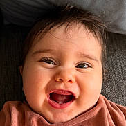 Elena a rejoint le concours — aidez-le/la à gagner de superbes lots ! baby, infant, smiling, laugh, eyes, eyelashes, teeth, mouth_open, chubby_cheeks, close_up, face, hair, tousled_hair, couch, pillow, clothing, portrait, joyful, happy, natural_light