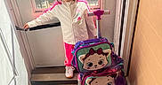 Legna is registered to the contest to win money with this photo: child, girl, door, window, suitcase, luggage, cat_face, pink, white_jacket, floor, sunlight, indoor, handle, car_outside, hair_bow, wood_floor, standing, casual_clothing, person, daylight