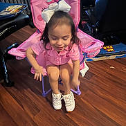 Angel joined the competition — help win amazing prizes! child, girl, pink_chair, white_bow, smiling, indoor, wooden_floor, sneakers, casual, happy, seated, furniture, room, toy, person, young, hair_accessory, flooring, playful, clothing