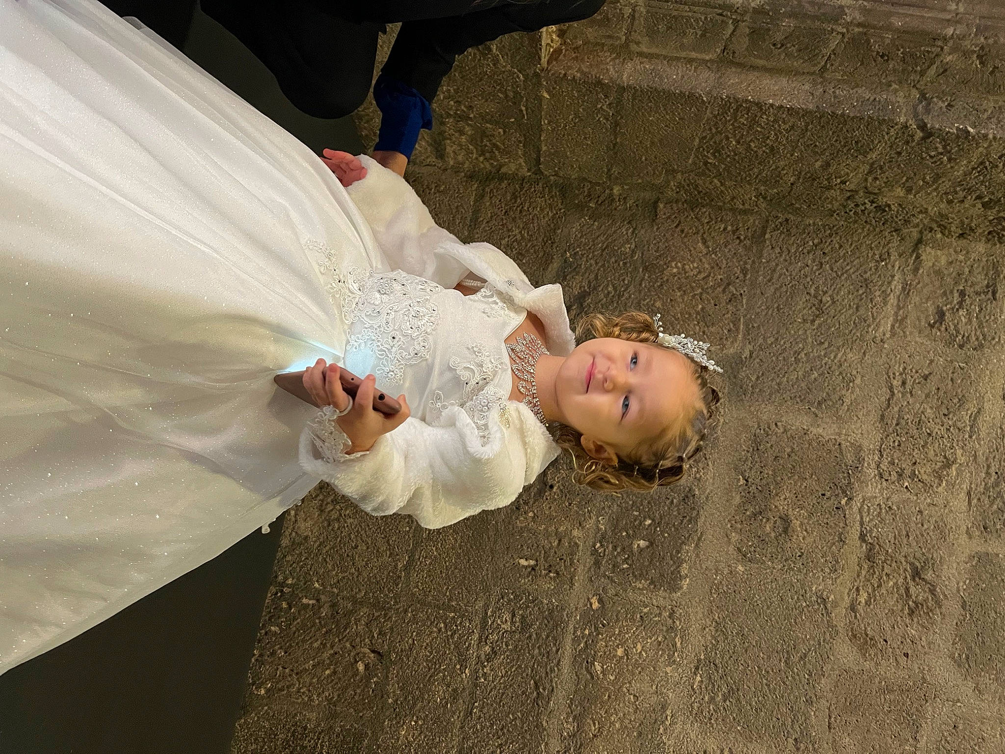 Taïsana participe au concours pour gagner de l'argent avec cette photo : bridal_accessory, bridal_clothing, bridal_veil, bride, child, dress, event, fashion_accessory, flash_photography, flooring, formal_wear, gesture, grass, happy, person, toddler, tradition, tree, veil, wedding_dress