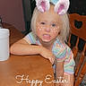 blonde_hair, bunny_ears_filter, carpet, child, child_interior, child_leaning, cute, digital_filter, doorway, easter, face_filter, fun, happy_easter_text, home, indoor, playful_expression, striped_clothing, table, wooden_chair, wooden_furniture